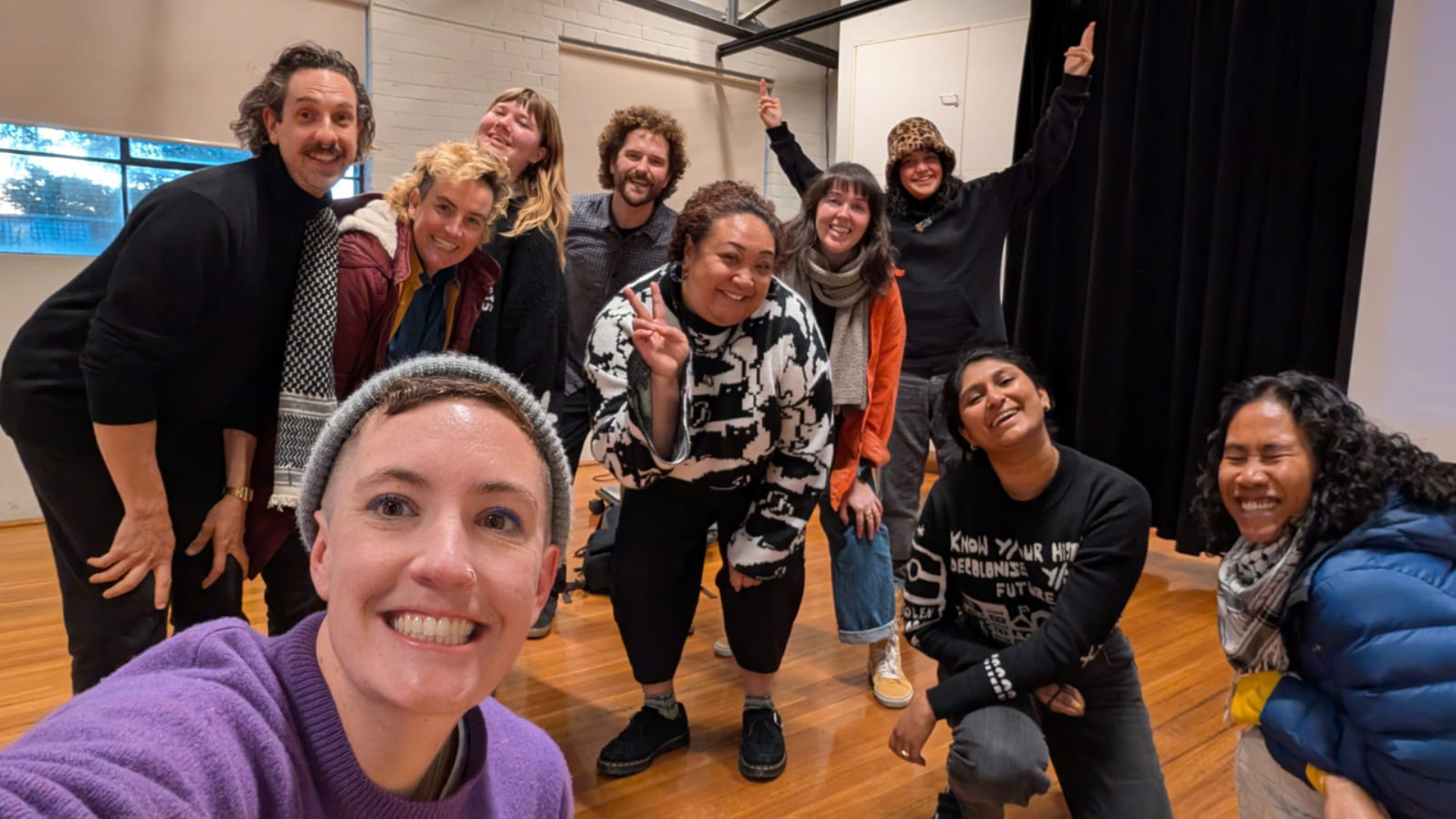 Members of 350’s Climate Justice Coalition pose together indoors on a wooden floor, smiling toward the camera at a group meeting. 
